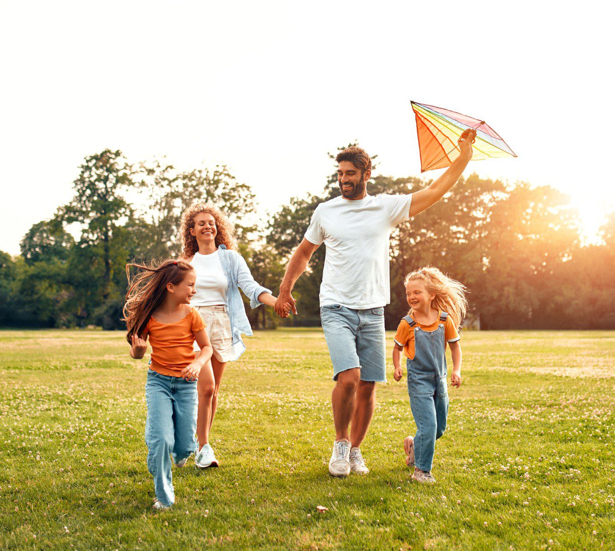 Family flying kite in a sunny park.