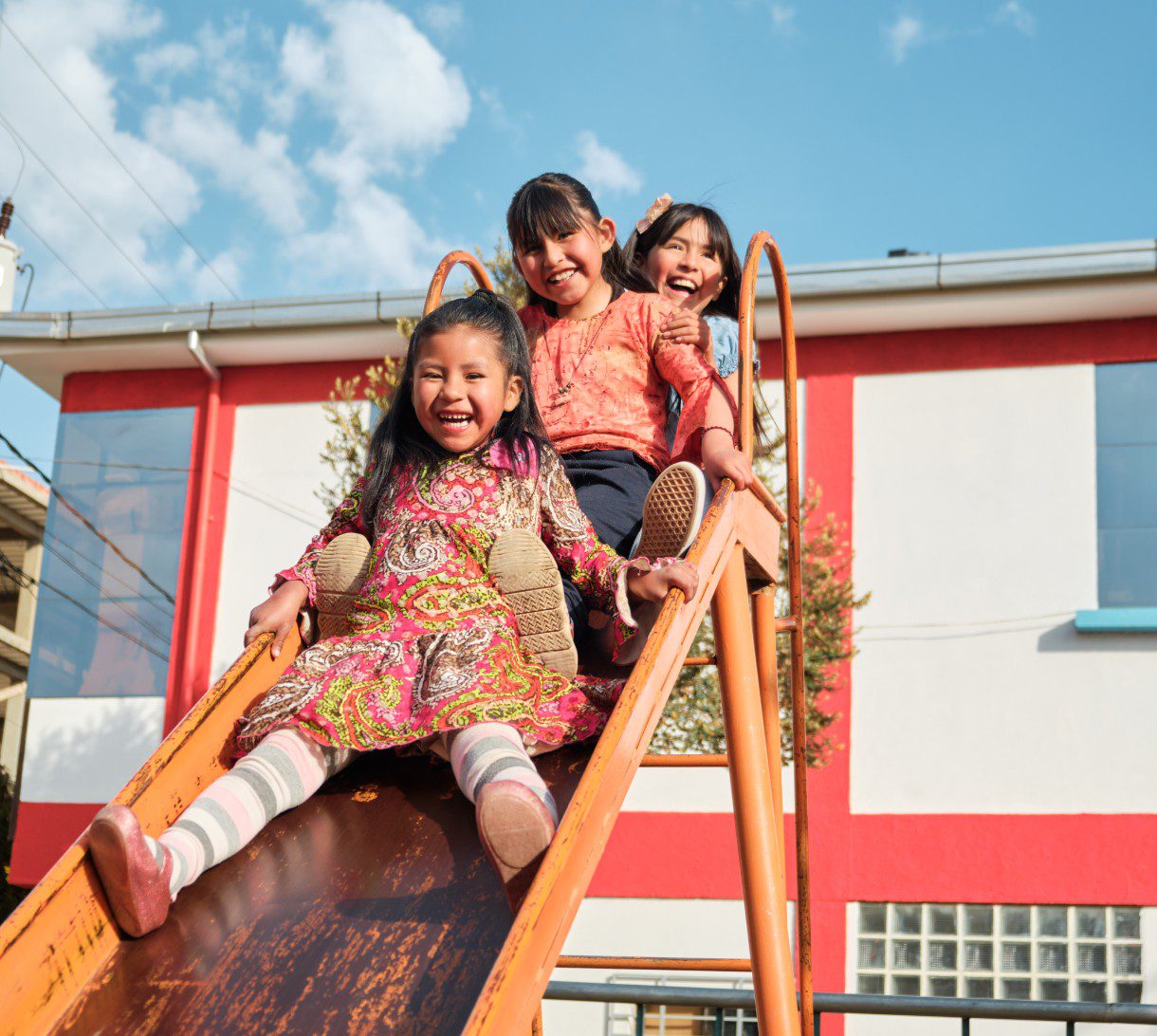 Children happily sliding down playground slide.