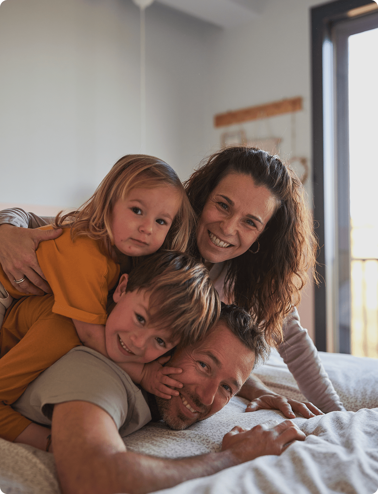 Happy family piling on a bed.
